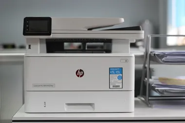 Biała drukarka HP LaserJet Pro MFP stojąca na biurku w biurze.