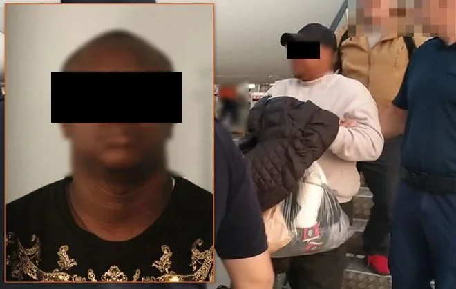 Zatrzymanie mężczyzny w czarnej czapce i białej bluzie przez funkcjonariuszy w mundurach na schodach wewnątrz budynku.