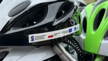 Rowerowe kaski z naklejkami informującymi o dofinansowaniu z funduszy europejskich.