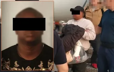 Zatrzymanie mężczyzny w czarnej czapce i białej bluzie przez funkcjonariuszy w mundurach na schodach wewnątrz budynku.
